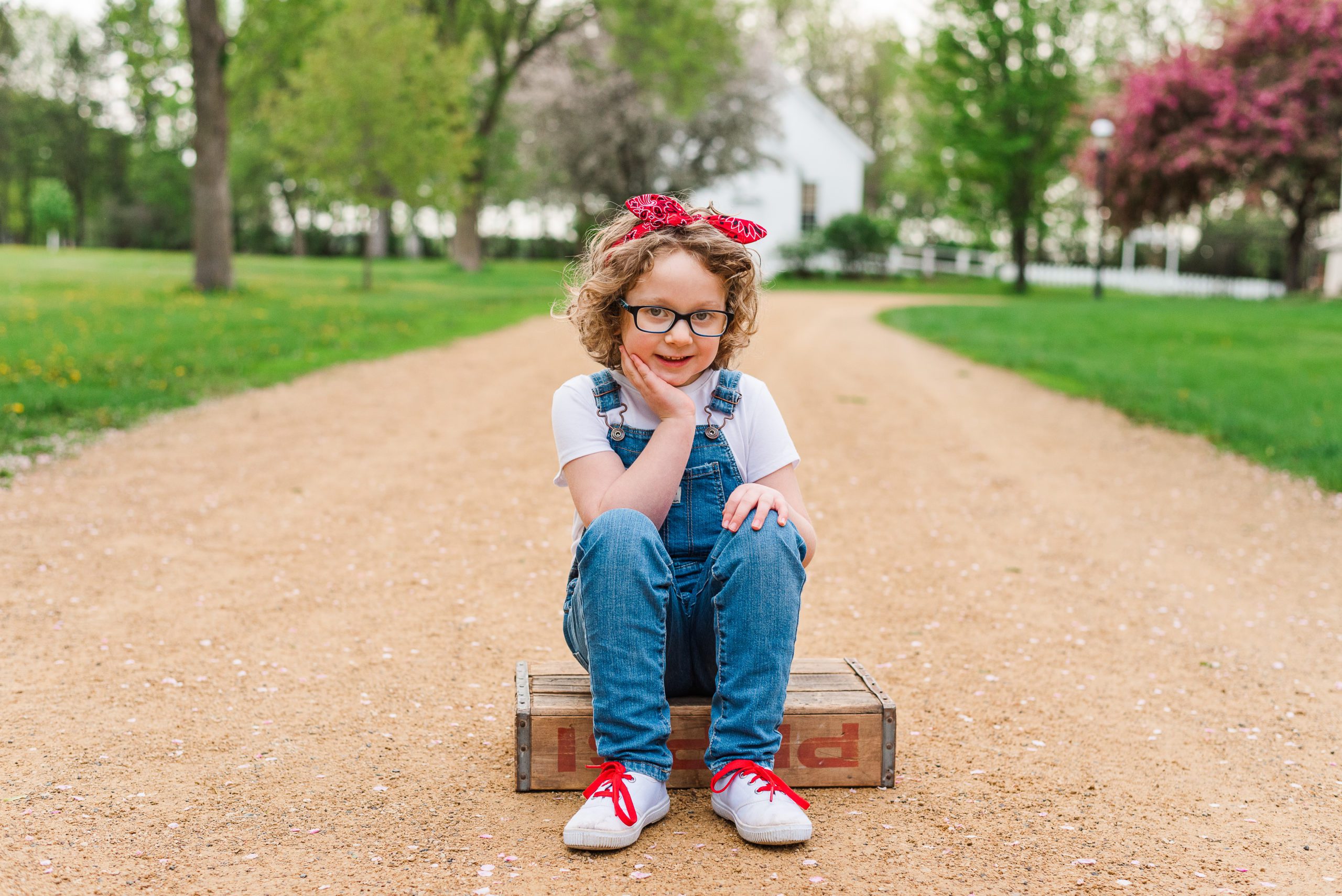 girl sitting on wooden box with red bandana and overalls